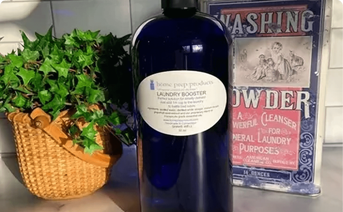 A blue bottle of laundry booster powder with decorative plants and vintage signs.
