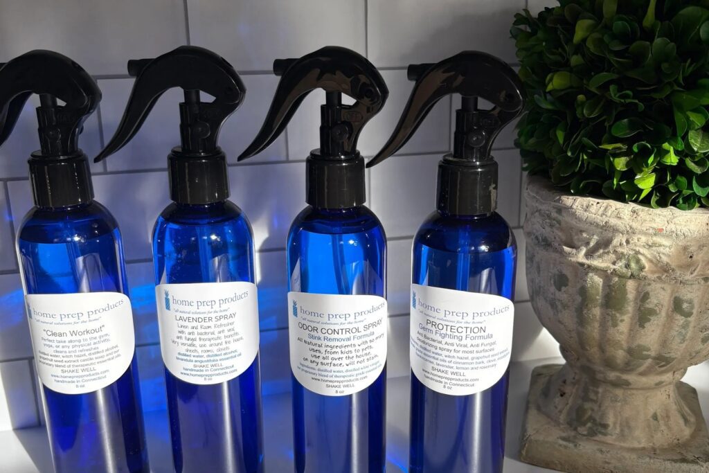 Blue spray bottles with white labels lined up on a shelf.